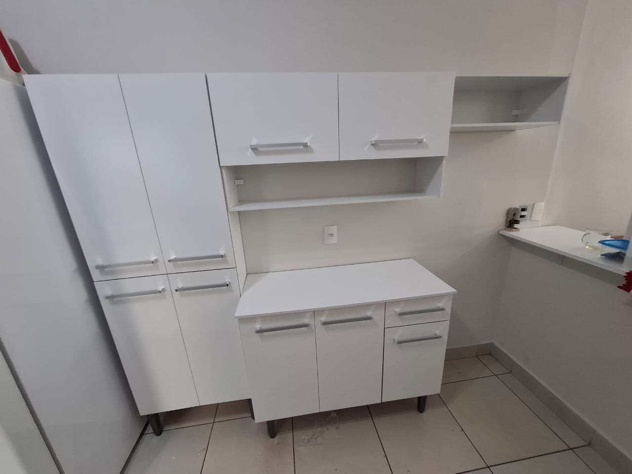 Cozinha compacta branca montada: torre de armários, aéreos com nicho e balcão de duas portas com gavetas