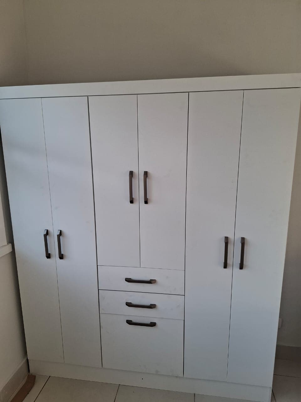 Guarda-roupa branco de seis portas com três gavetas centrais e puxadores escuros