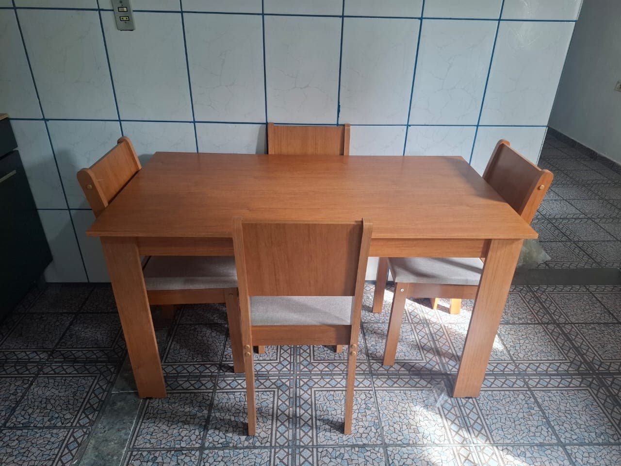Mesa de jantar de madeira com quatro cadeiras estofadas, montada na cozinha