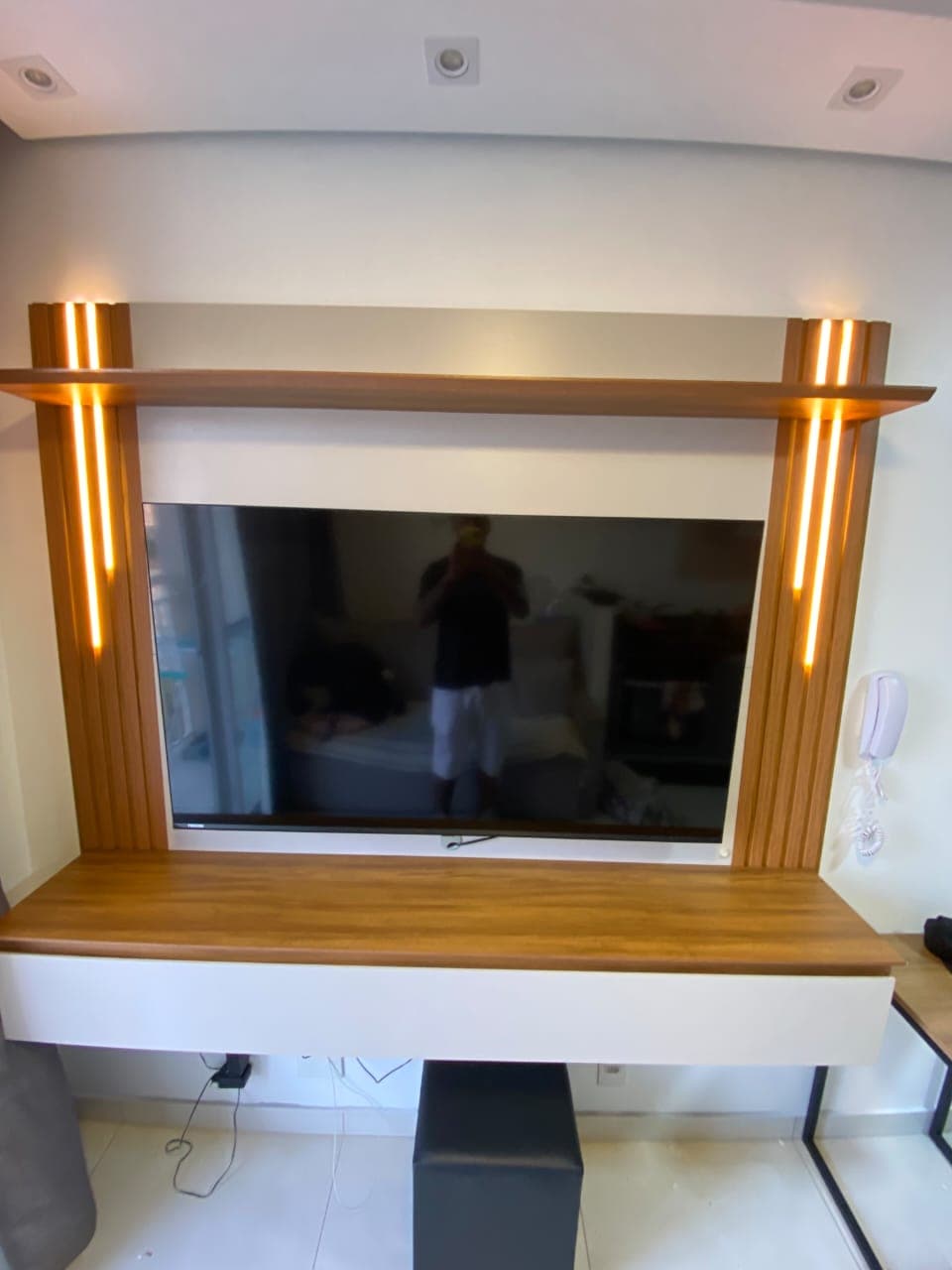 Painel de TV com colunas ripadas iluminadas por LED, prateleira superior e rack suspenso branco
