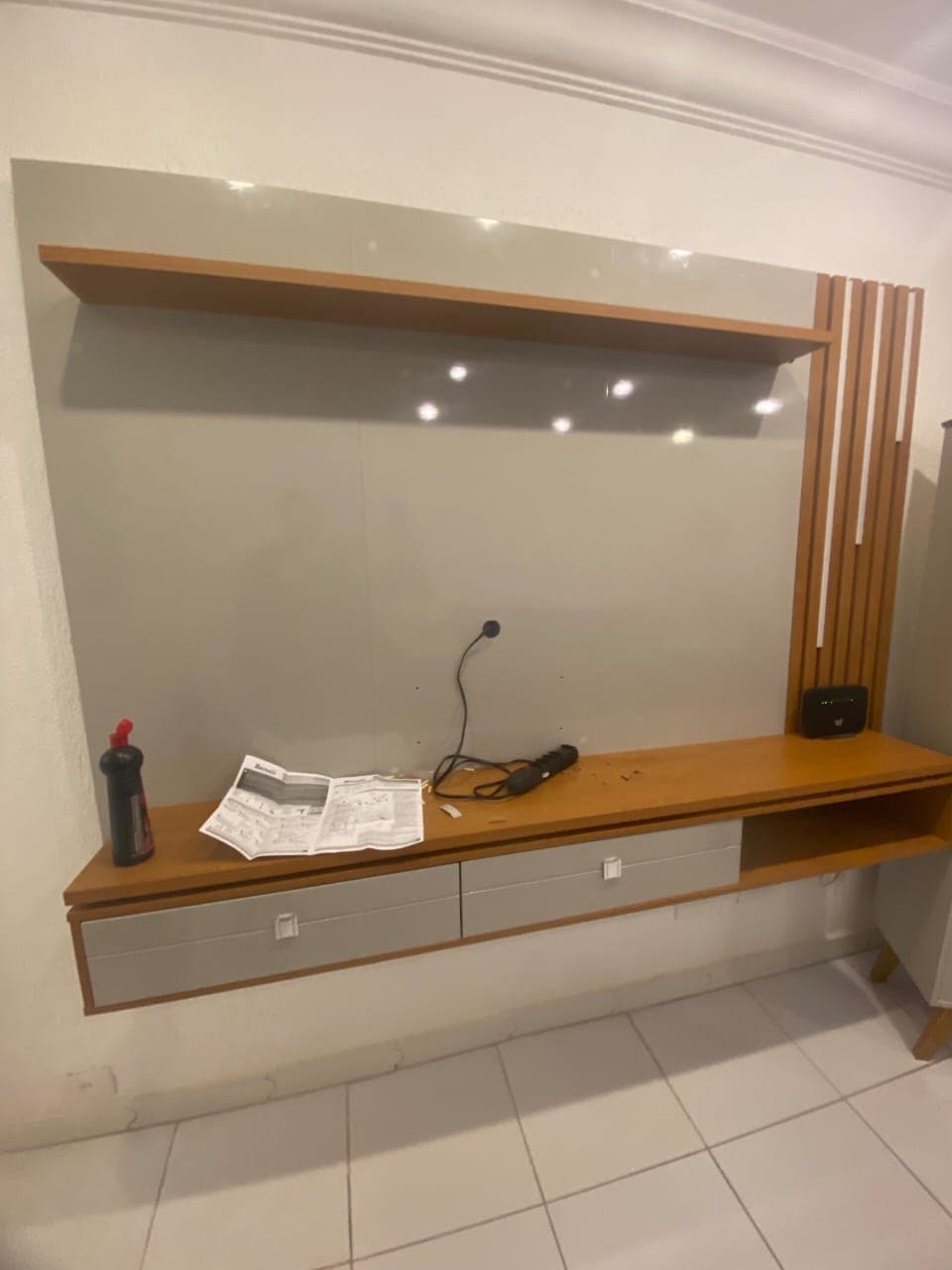 Painel de TV suspenso com detalhe ripado lateral, prateleira e bancada com gavetas